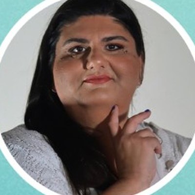 Filipa Miranda, de cabelo preto comprido e casaco branco de malha, apoia o queixo na mão sobre fundo claro.