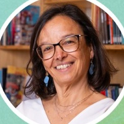 Margarida Rodrigues, de óculos e cabelo escuro pelos ombros, sorri à frente de uma estante cheia de livros.